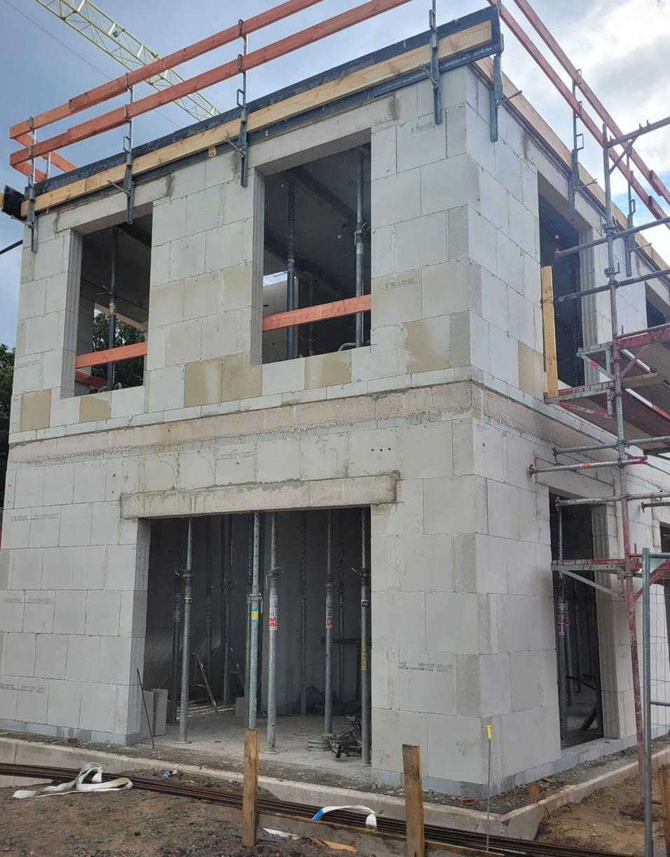 Bau eines zweigeschossigen Hauses mit unvollendeter Fassade und Baugerüst, sichtbar sind Fensteröffnungen.