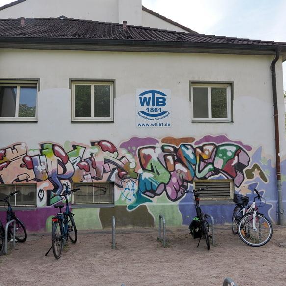 Graffiti mit bunten Buchstaben an einer Wand, davor stehen mehrere Fahrr&auml;der an einem Fahrradst&auml;nder.
