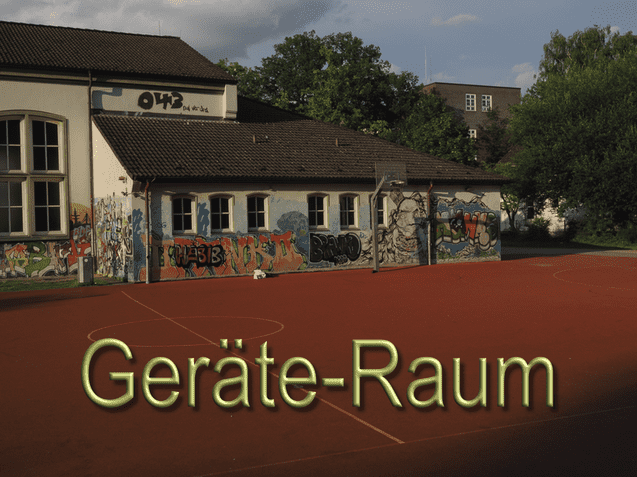Graffiti-bedeckte Wand eines Ger&auml;te-Raums an einem Sportplatz mit rotem Belag und B&auml;umen im Hintergrund.