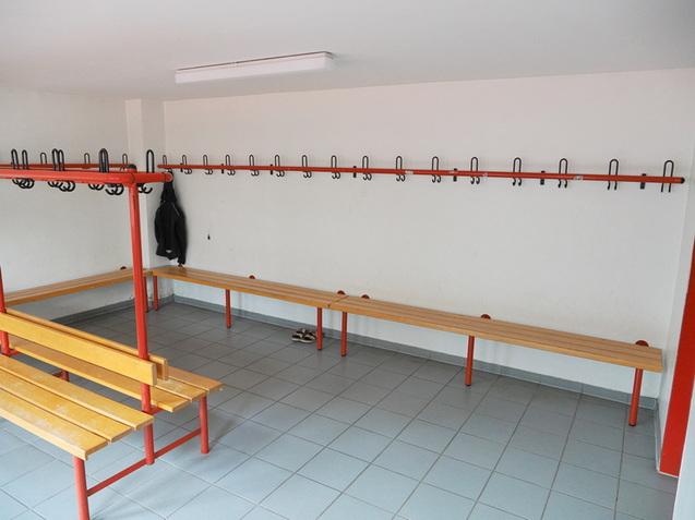 Leere Umkleidekabine mit Haken f&uuml;r Kleidung und Holzbank in einer lichtdurchfluteten Umgebung.