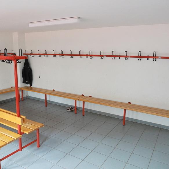 Leere Umkleidekabine mit Haken f&uuml;r Kleidung und Holzbank in einer lichtdurchfluteten Umgebung.