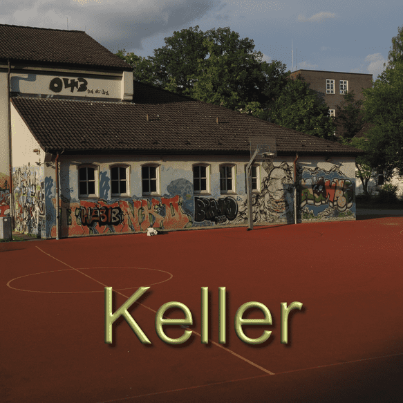 Schulgeb&auml;ude mit bunten Graffiti an der Wand, davor ein orangefarbener Sportplatz mit Basketballkorb.