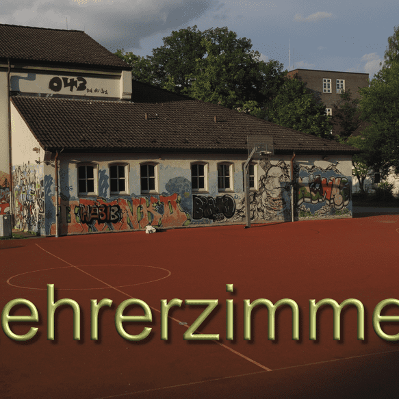 Graffiti-bedeckte Wand eines Lehrerzimmers an einem roten Sportplatz unter einem bew&ouml;lkten Himmel.