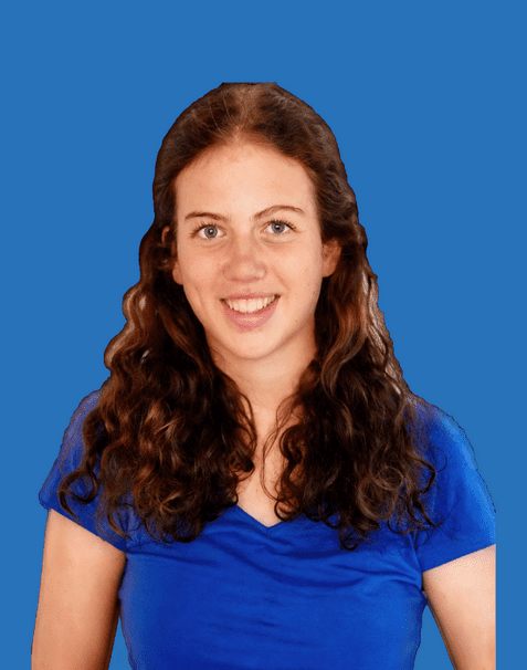 Junge Frau mit lockigem, braunem Haar, lächelt in einem blauen Shirt vor einem einfarbigen blauen Hintergrund.