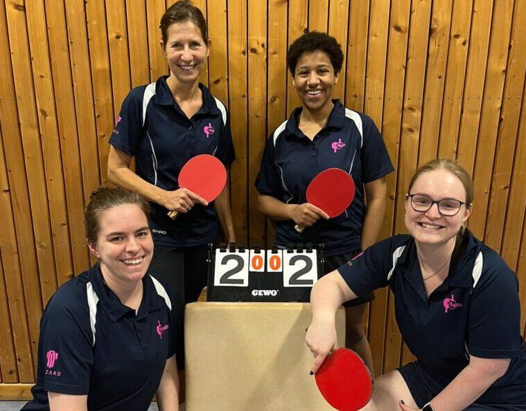 Vier Frauen in Sportkleidung halten Tischtennisschläger vor einem Punktestand von 2:2 in einem Tischtennisraum.