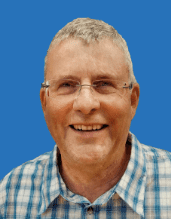 Lächelnder Mann mit kurzen grauen Haaren, Brille und kariertem Hemd auf blauem Hintergrund.