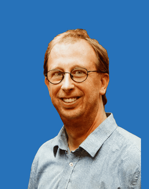 Porträt eines lächelnden Mannes mit Brille und Hemd vor blauem Hintergrund.