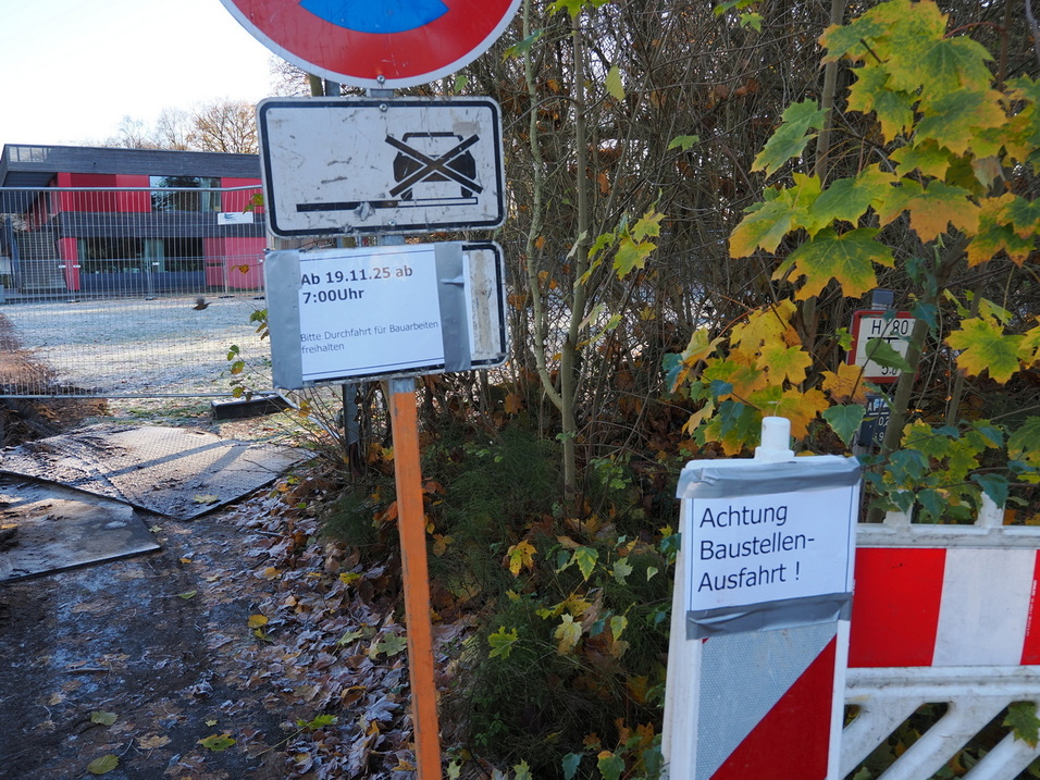 Stra&szlig;ensperrungsschild mit Baustellenhinweisen und Warnhinweis an einem unbefestigten Weg unter B&auml;umen.