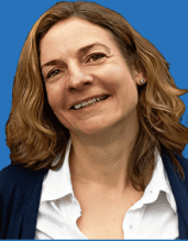 Portrait einer Frau mit lockigem Haar, die in die Kamera lächelt, vor einem blauen Hintergrund.