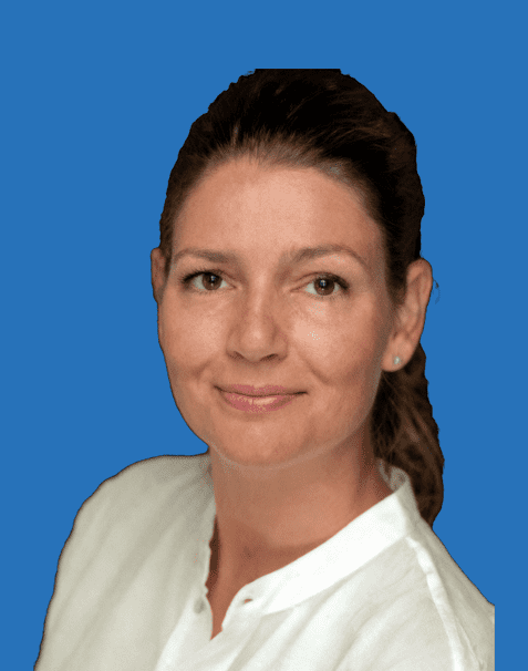 Portr&auml;t einer l&auml;chelnden Frau mit langen, braunen Haaren vor blauem Hintergrund, wearing a wei&szlig;e Bluse.