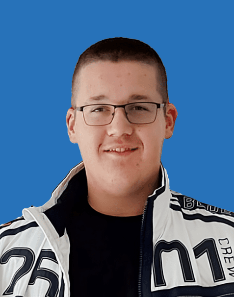 Porträt eines lächelnden Jugendlichen mit Brille, in einer schwarzen T-Shirt und einer weißen Jacke, vor blauem Hintergrund.