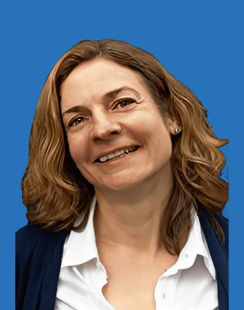 Porträt einer lächelnden Frau mit lockigem Haar, vor einem blauen Hintergrund, in einer weißen Bluse und dunkler Jacke.