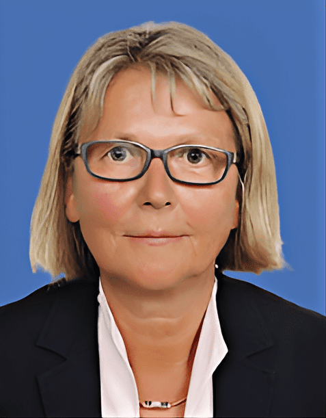 Porträt einer Frau mit blonden, schulterlangen Haaren, die eine schwarze Blazerjacke und eine helle Bluse trägt.